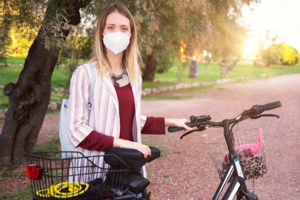 woman wearing mask holding bicycle